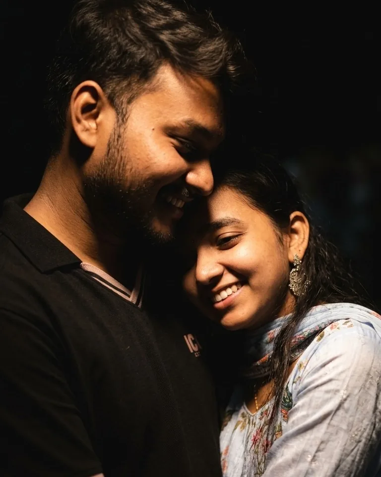 The couple smiling together in a warm spotlight